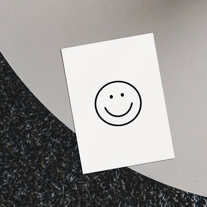 weiße Postkarte DIN A5 mit schwarzen Smiley